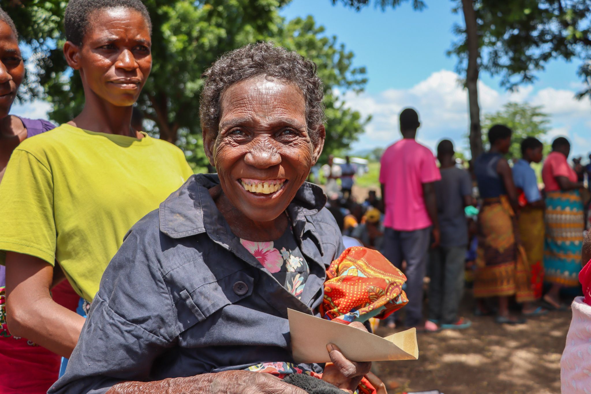 Kvinde fra Malawi står i kø for at få udleveret kontanter af Folkekirkens Nødhjælp i Malawi.
