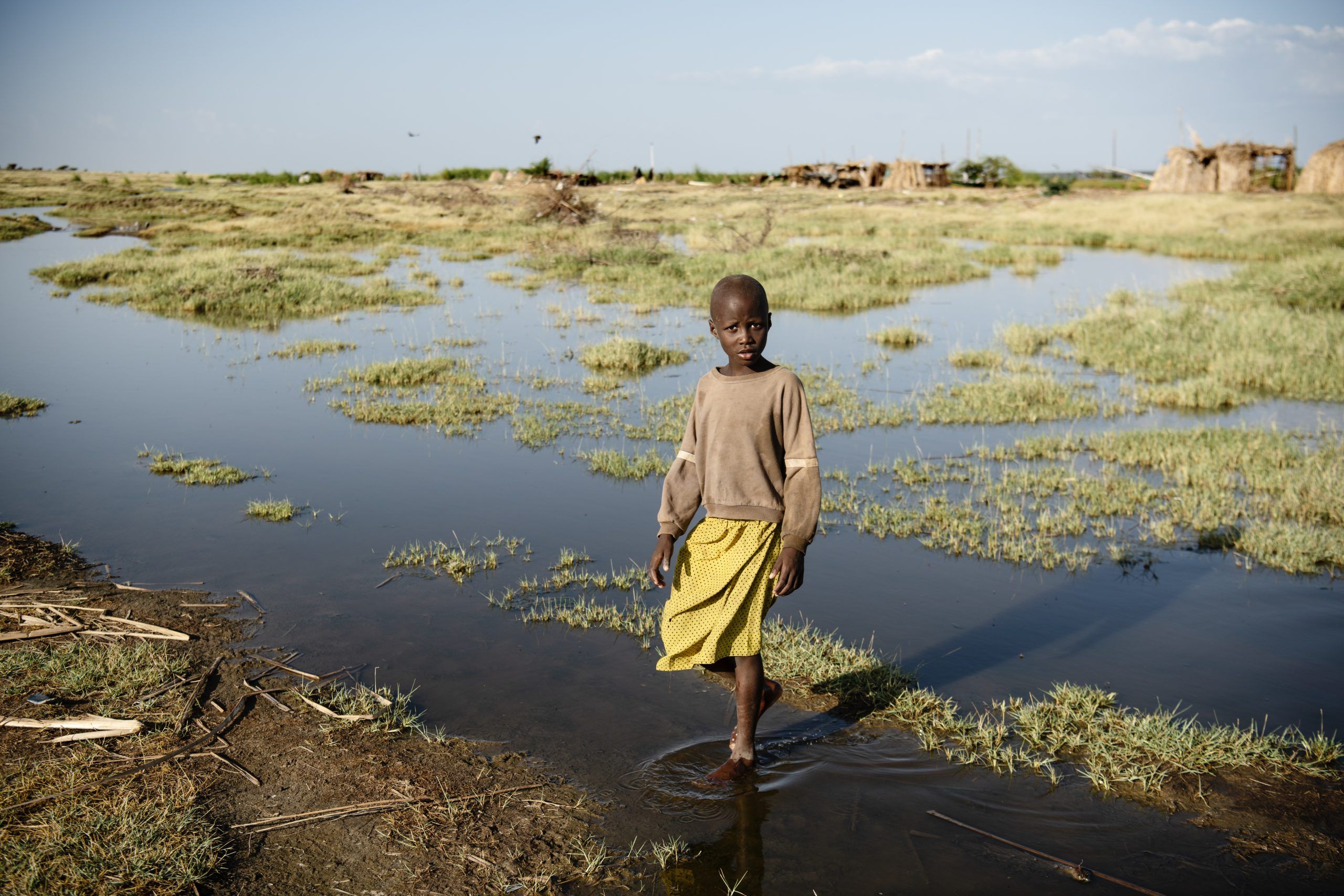 Aminit, pige fra Kenya i gul kjole står i vand