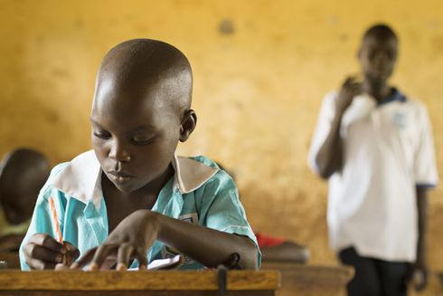 Dreng skriver med blyant på skolebænken