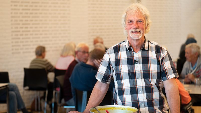Knud Anker står klar med aftensmaden på et rullebord.