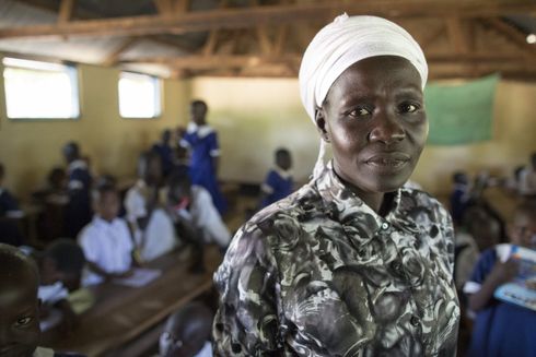Skolelærer, Lucy, står i klasselokale i Kenya og kigger direkte på kameraet