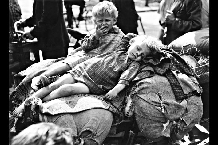 Sort hvid billede af to børn, der ligger på sække. Det ene barn sover og det andet barn græder