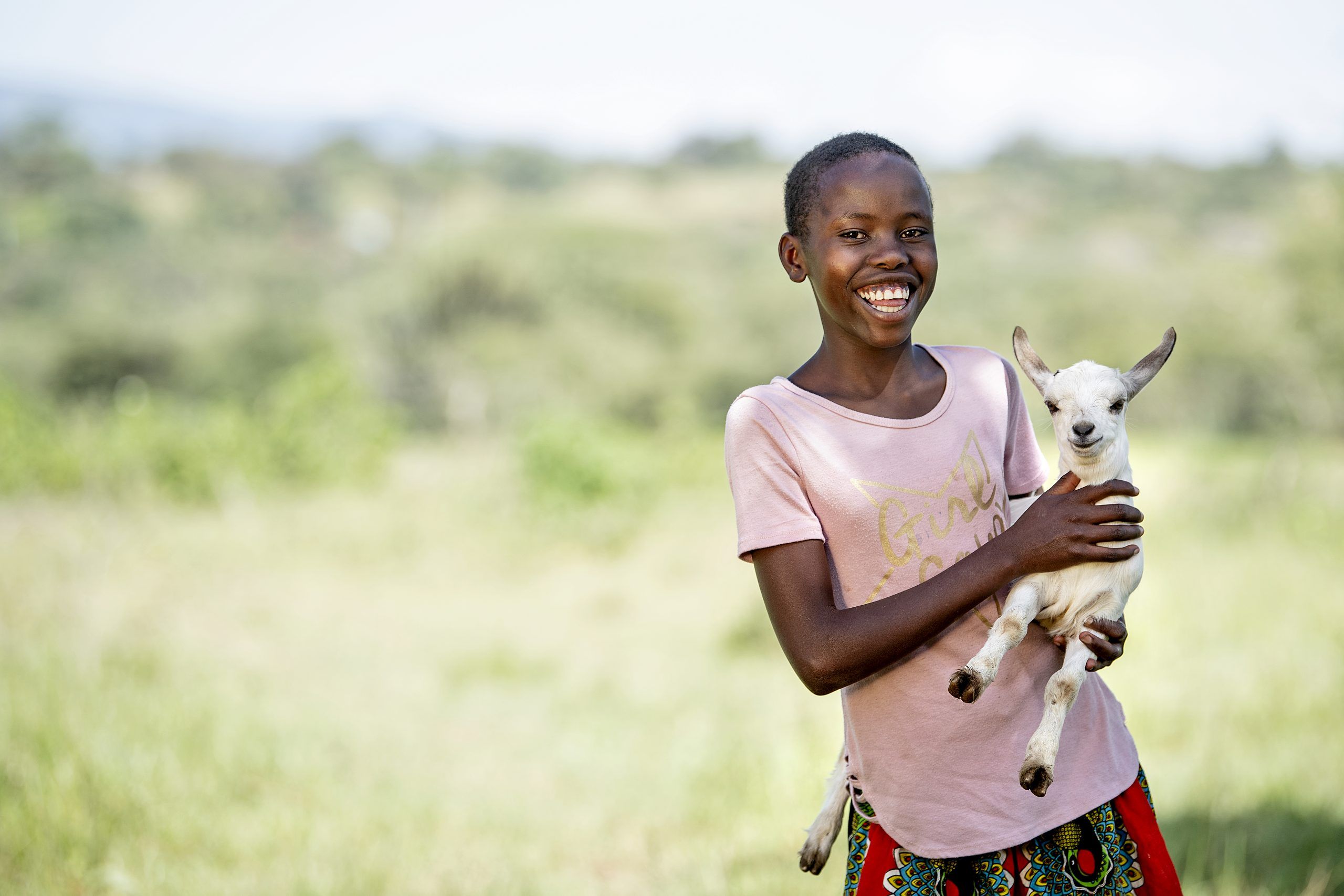 Smilende pige står med en ged i Kenya - Giv en ged
