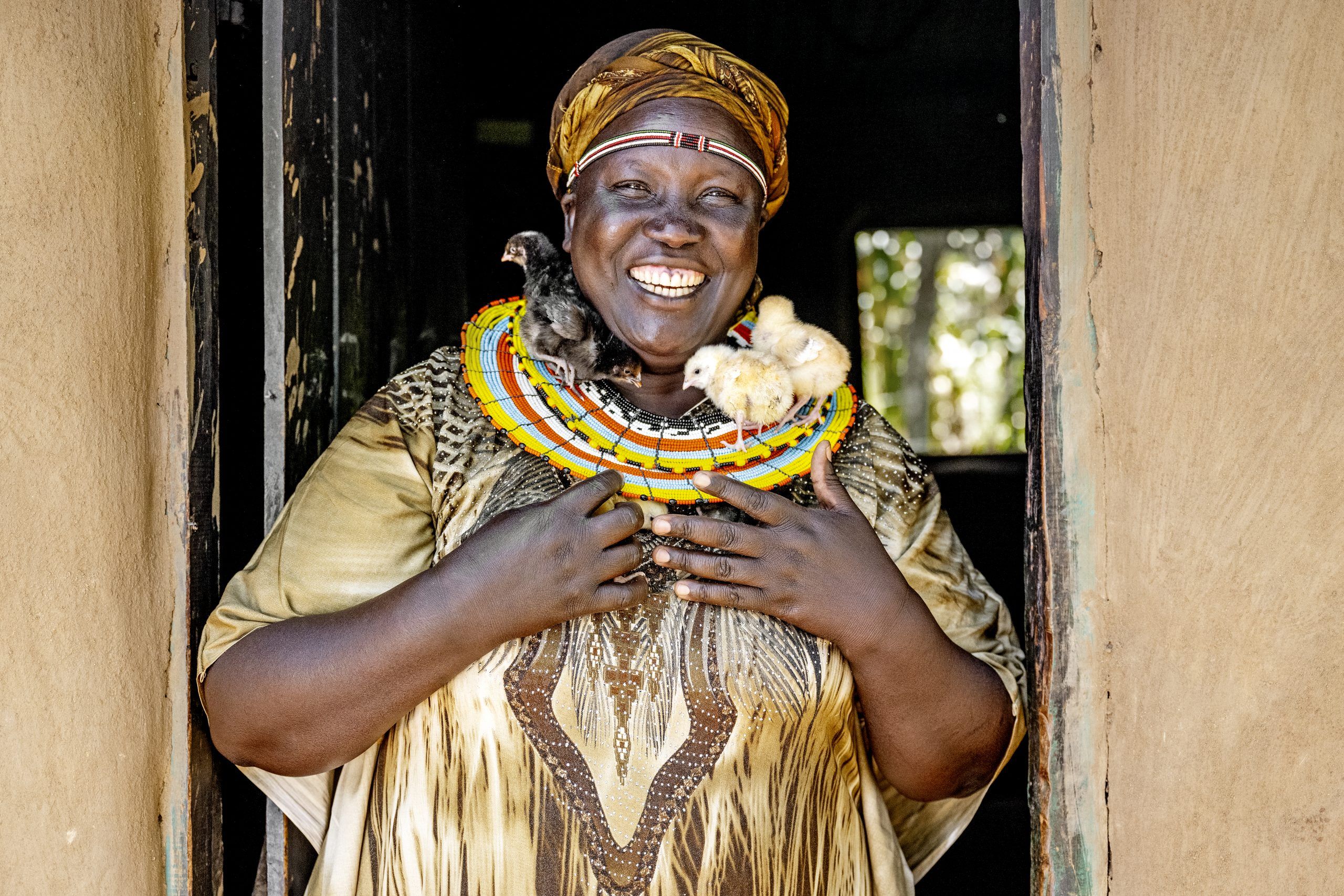 Lucy from Kenya is smiling with chickens around her neck