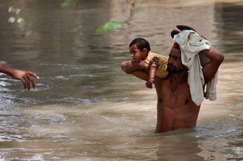 Man carrying his child through flood