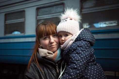 Kvinde med barn i armene står på togstationen i Lviv, Ukraine