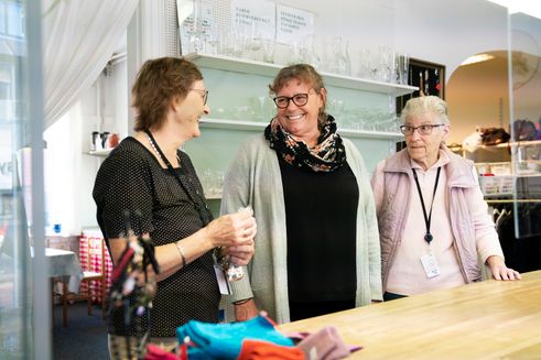 Tre kvinder smiler til hinanden i en genbrugsbutik