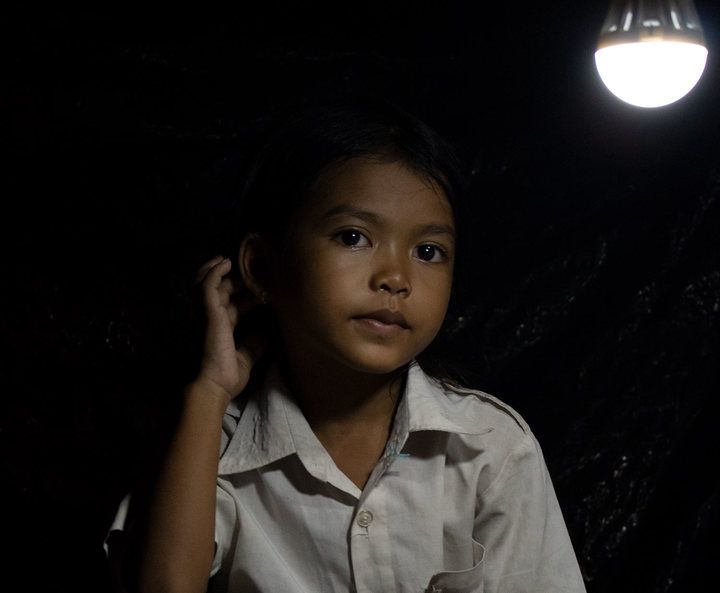 thida, en pige fra Cambodia, sidder under en solcellelampe