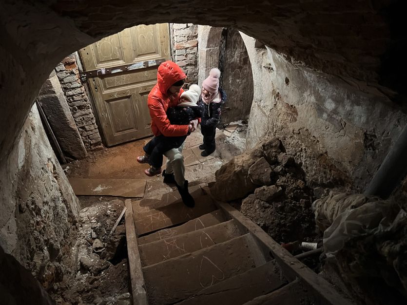 En kvinde og to børn forlader en kælder i Lviv, som er omdannet til et bombehus