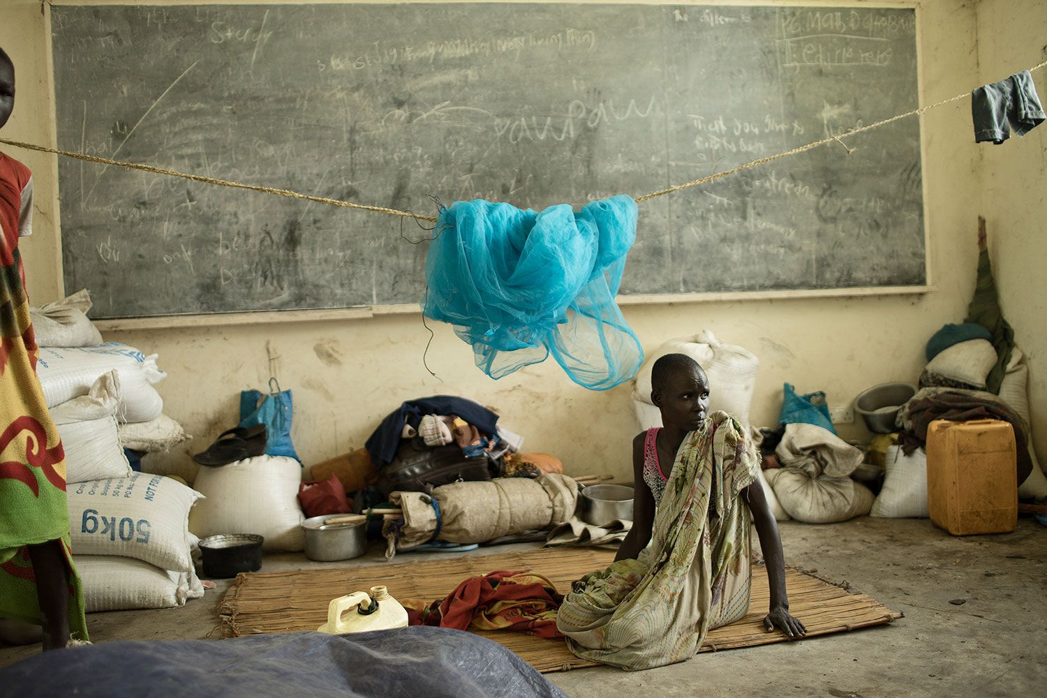 Kvinde ligger på gulv foran tavle på nedlagt skole