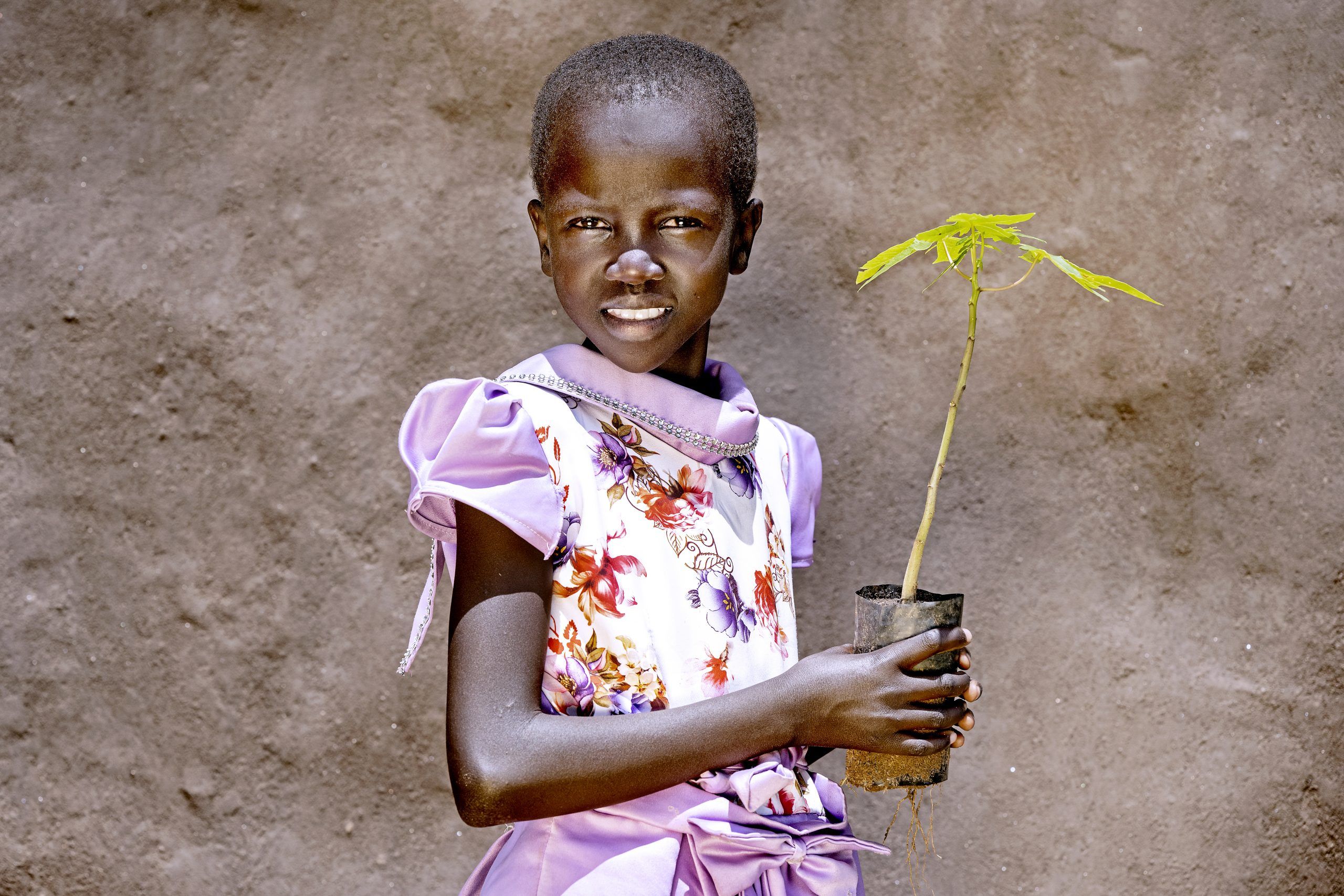 Pige med lilla kjole står med en træspire i hånden